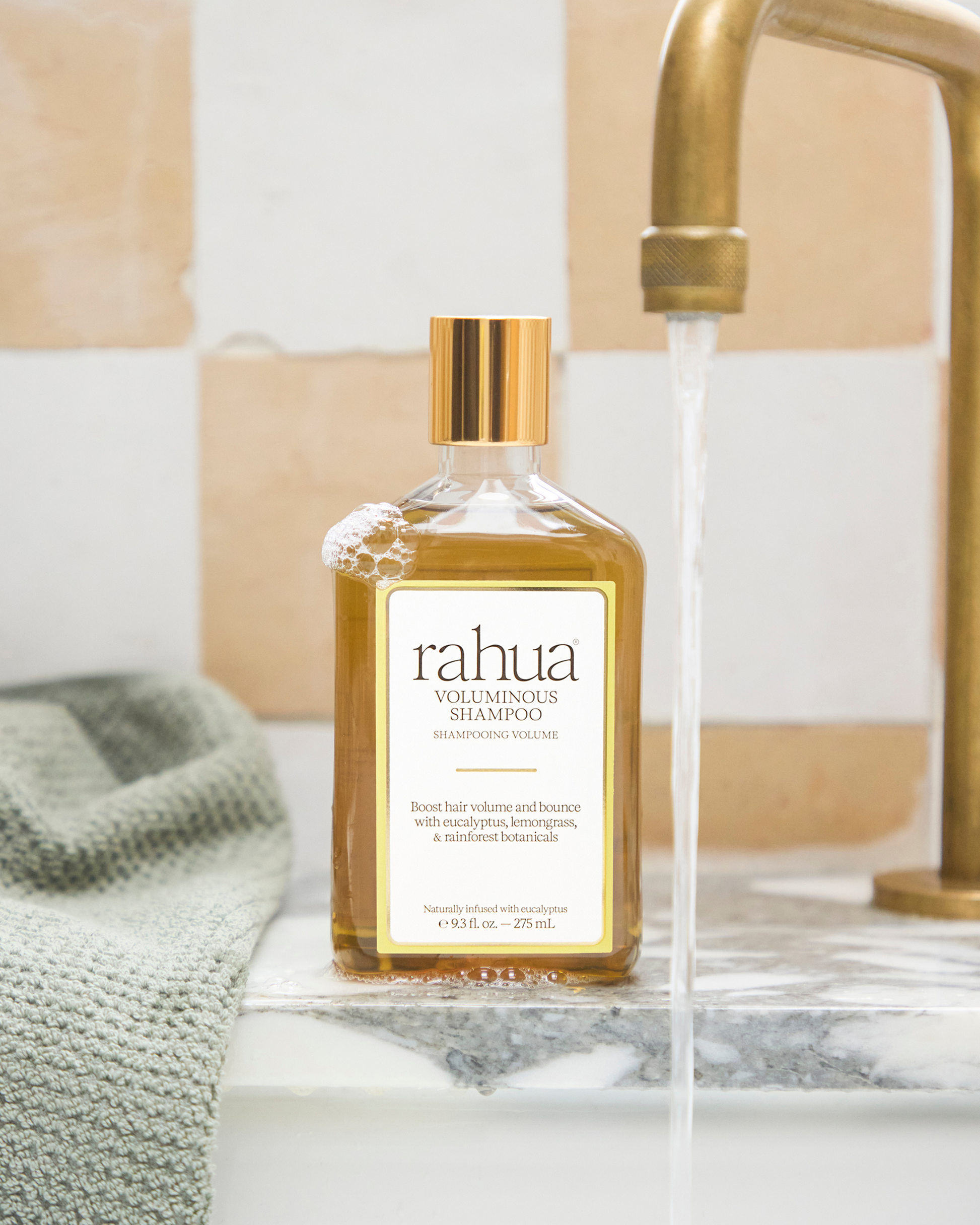 rahua shampoo bottle on a bathroom counter with running water|variant:93-oz,18-oz